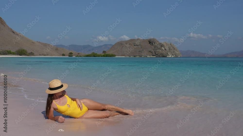 Young slim woman on vacation at Pink Beach of Komodo Island, slim young woman in swimsuit relaxing in tropics