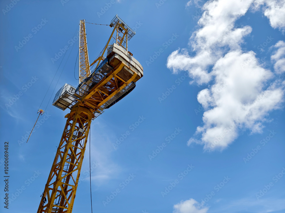 A large yellow crane stands out against a bright blue sky A large yellow crane stands out against a bright blue sky