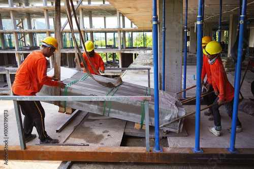 Workers at a building under construction take slabs from a crane