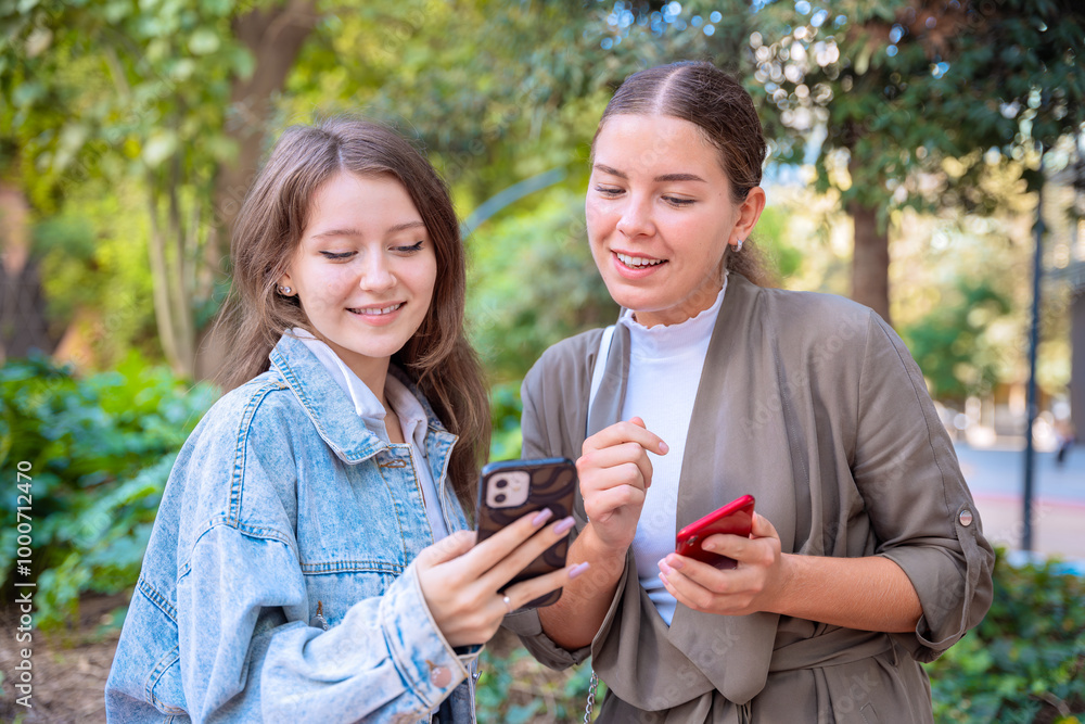 two happy teenage friends using smartphone app outdoors. two happy teenage friends using smartphone app outdoors.