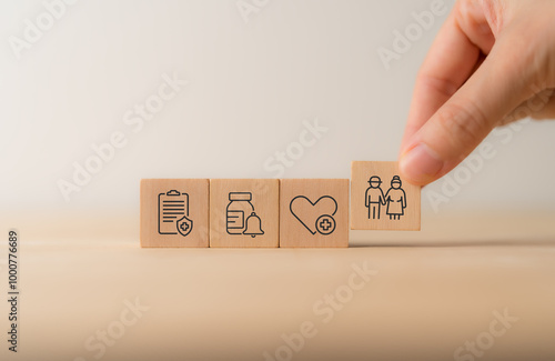 Elderly care concept. Hand holds wooden cubes with icons related to elderly care, medical, rehabilitation service, nursing care for enhancing quality of life in elder people. Used banner, brochure. photo