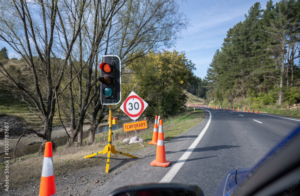 Temporary traffic light control on the side of the road. Cars stopped at the roadwork red light. Hawke’s Bay.