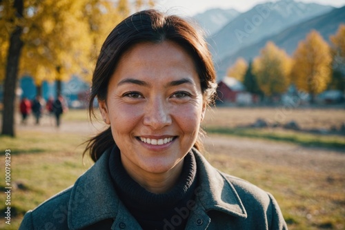 Close portrait of a smiling 40s Kyrgyz woman looking at the camera, Kyrgyz outdoors blurred background photo