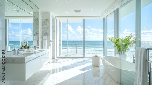 A contemporary coastal bathroom, with white marble floors, sleek fixtures, and floor-to-ceiling windows framing views of the ocean