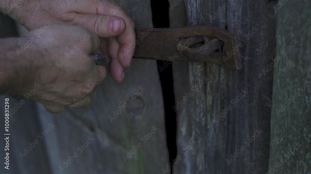 In a quiet rural setting, a man carefully locks the weathered doors of an old barn with a sturdy padlock, ensuring its secrets remain safe for years to come. In a quiet rural setting, a man carefully locks the weathered doors of an old barn with a sturdy padlock, ensuring its secrets remain safe for years to come.
