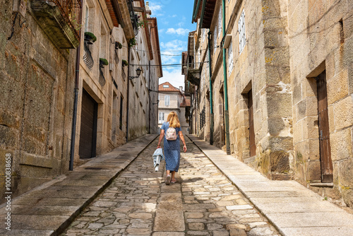 Tourist woman climbing the steep streets of the medieval town of Tui in Galicia.