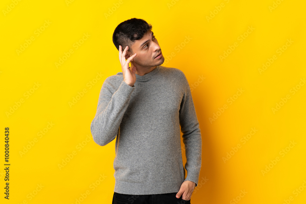 Young Colombian man isolated on yellow background thinking an idea Young Colombian man isolated on yellow background thinking an idea