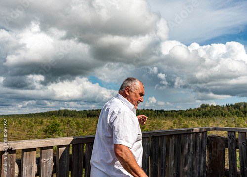 wooden footbridge in the bog, a man walks in the bog, traditional bog vegetation, Nigula nature reserve is Nigula bog, a typical western Estonian bog photo