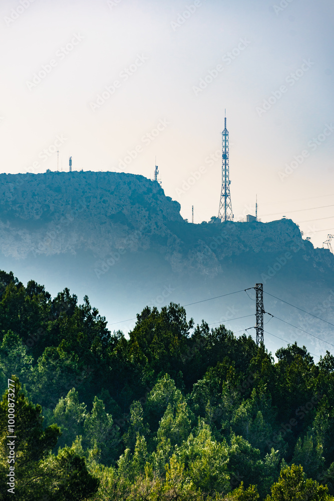 Obraz premium Tower mast and electricity transmission pylons in mountains