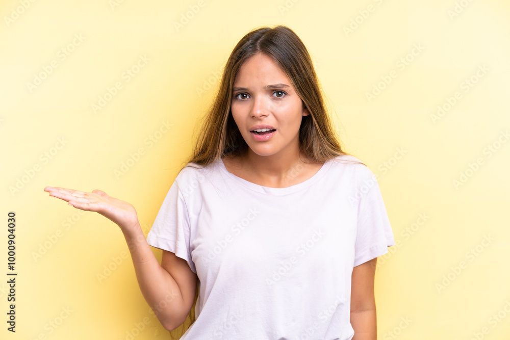 Young caucasian woman isolated on yellow background making doubts gesture Young caucasian woman isolated on yellow background making doubts gesture