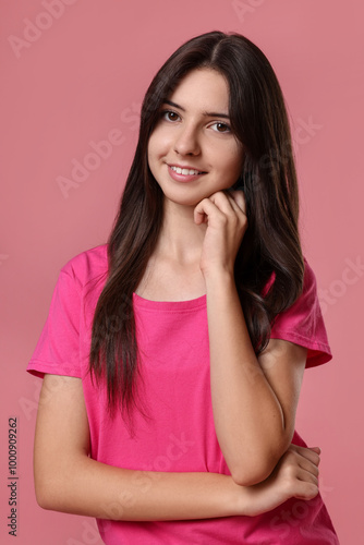 Portrait of cute teenage girl on pink background