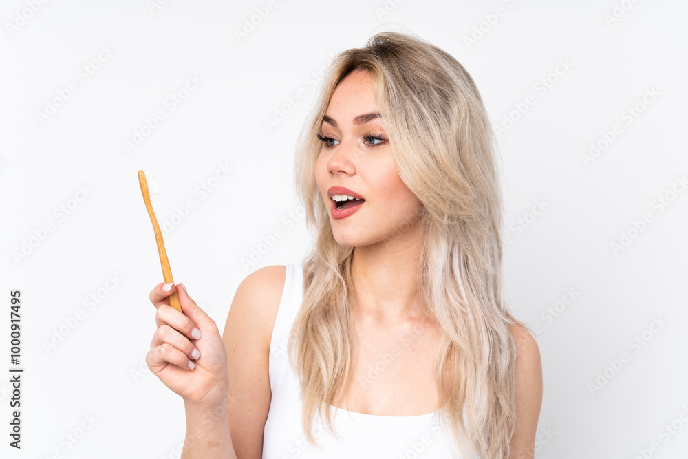 Teenager blonde girl over isolated white background with a toothbrush Teenager blonde girl over isolated white background with a toothbrush