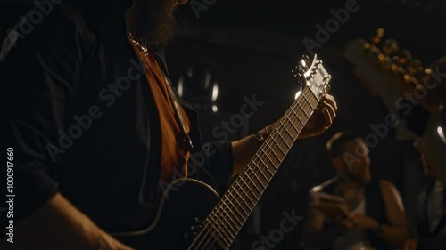 Midsection of two unrecognizable bass guitarists spending time rehearsing with bandmates at recording studio before live performance on stage