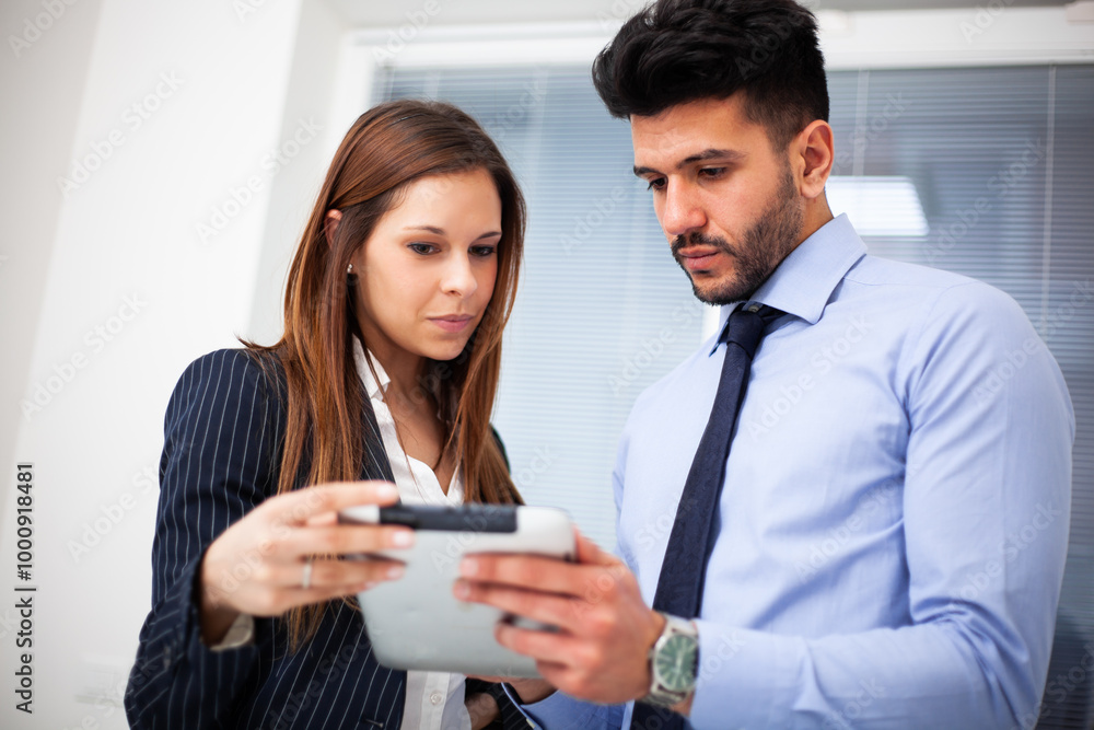 Two businesspeople discussing while looking at a tablet Two businesspeople discussing while looking at a tablet