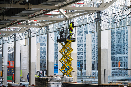 Electricians installing cables on cable trays working at height on construction site