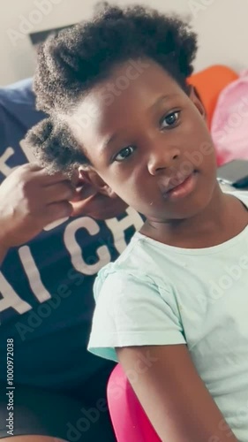 An African Woman Braiding her dauther's hair