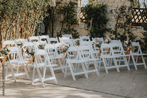 Stuhlreihen für eine freie Trauung einer Hochzeit draußen mit Blumenarrangement photo