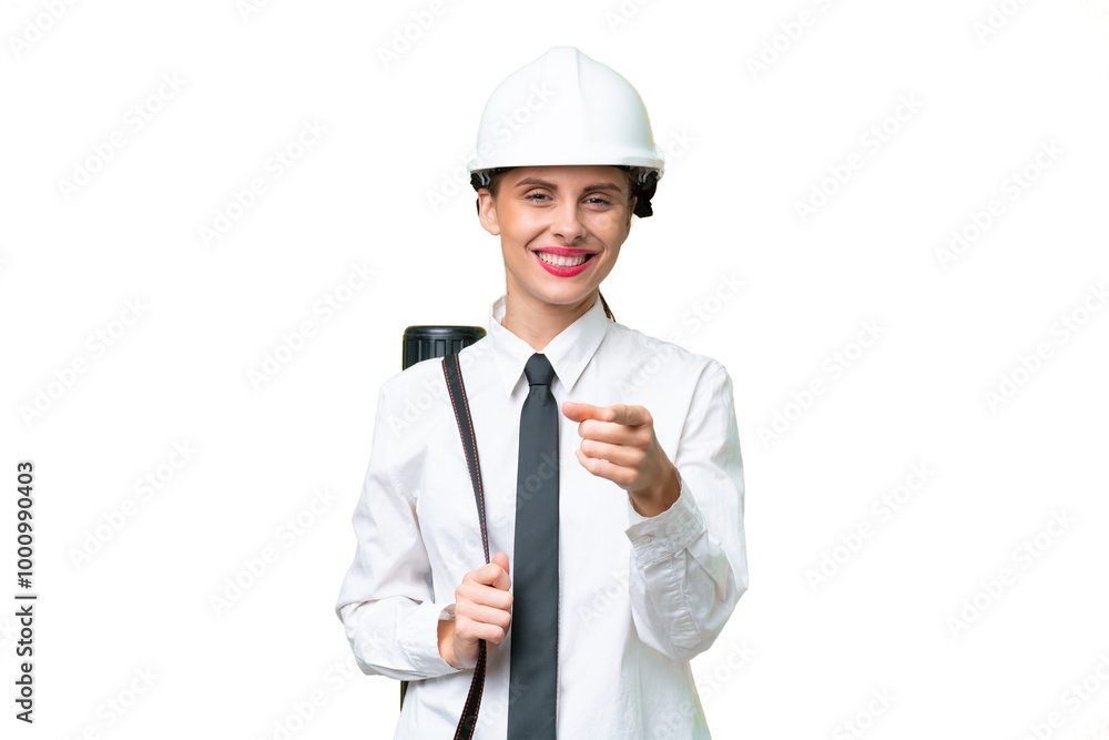 Young architect woman with helmet and holding blueprints over isolated background surprised and pointing front Young architect woman with helmet and holding blueprints over isolated background surprised and pointing front