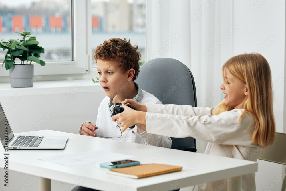 Obraz premium Happy Caucasian boy and girl studying and playing at home using laptops and headphones for online education and elearning They are sitting at a table in the living room, completely engrossed in their