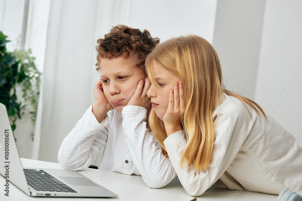 Happy siblings studying together at home using a laptop for online education The young boy and girl are sitting at a table in their living room, fully engaged in their elearning lessons With focused Happy siblings studying together at home using a laptop for online education The young boy and girl are sitting at a table in their living room, fully engaged in their elearning lessons With focused