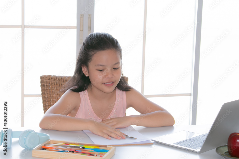 Adorable Asian girl online learning, writing notes while using a laptop, elementary school girl typing answer or response with teacher, Focus on digital communication and learning. Adorable Asian girl online learning, writing notes while using a laptop, elementary school girl typing answer or response with teacher, Focus on digital communication and learning.