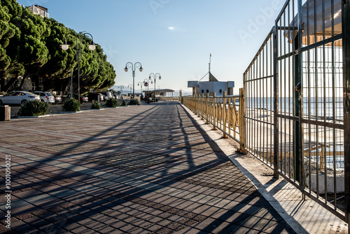 A long embankment along the sea with a fence.