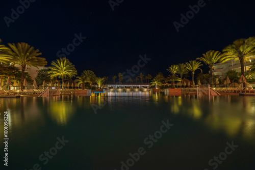 Wallpaper Mural Night view of illuminated poolside with palm trees and lounge chairs at tropical resort in Curacao. Torontodigital.ca