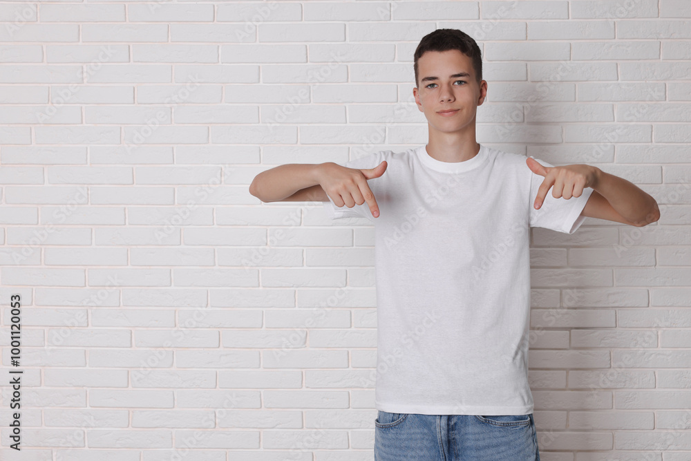Teenage boy wearing t-shirt near white brick wall, space for text Teenage boy wearing t-shirt near white brick wall, space for text