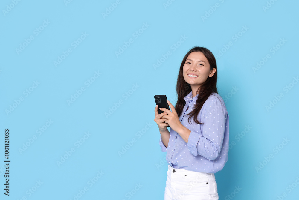 Smiling woman with smartphone on light blue background. Space for text Smiling woman with smartphone on light blue background. Space for text
