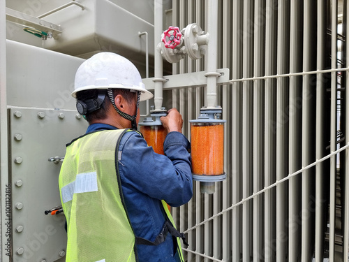 Foto Orange Silica Gel replacement activity by electrician for Silica Gel Breather at main tank and OLTC of 115kV/22kV power transformer