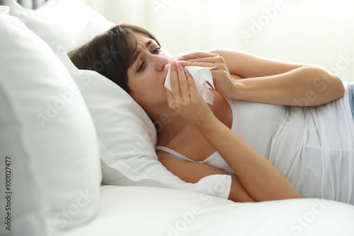 Woman with napkin suffering from sinusitis on bed