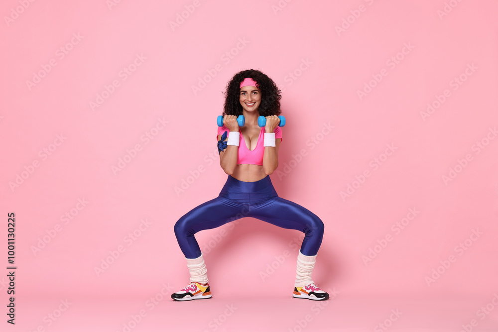 Woman doing aerobic exercise with dumbbells on pink background Woman doing aerobic exercise with dumbbells on pink background
