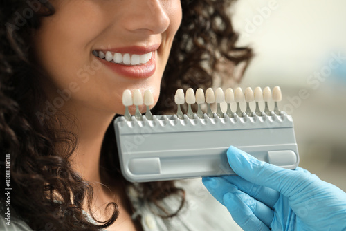 Фотография Doctor checking young woman's teeth color in clinic, closeup