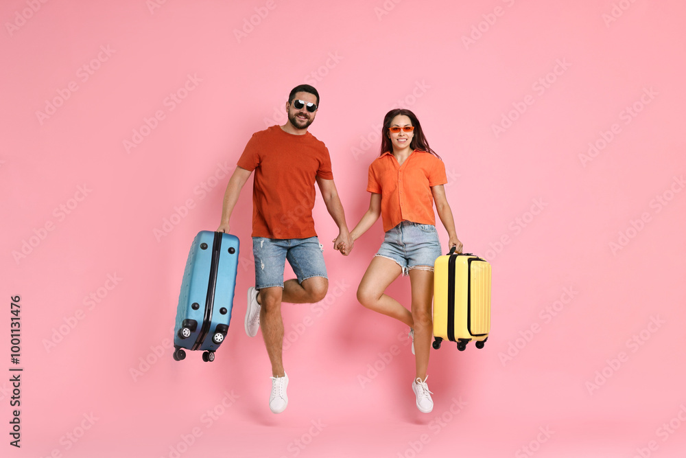 Happy woman and man with suitcases jumping on pink background Happy woman and man with suitcases jumping on pink background