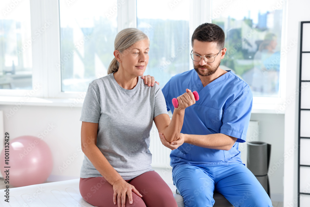 Obraz premium Senior patient exercising under physiotherapist supervision in rehabilitation center
