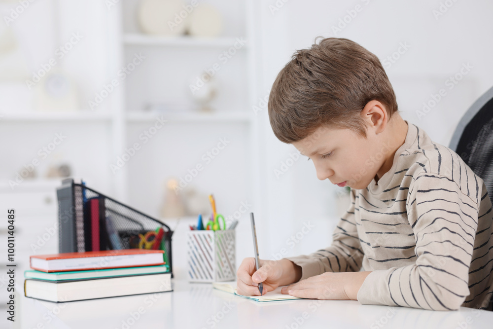 Boy with incorrect posture doing homework at white desk indoors Boy with incorrect posture doing homework at white desk indoors