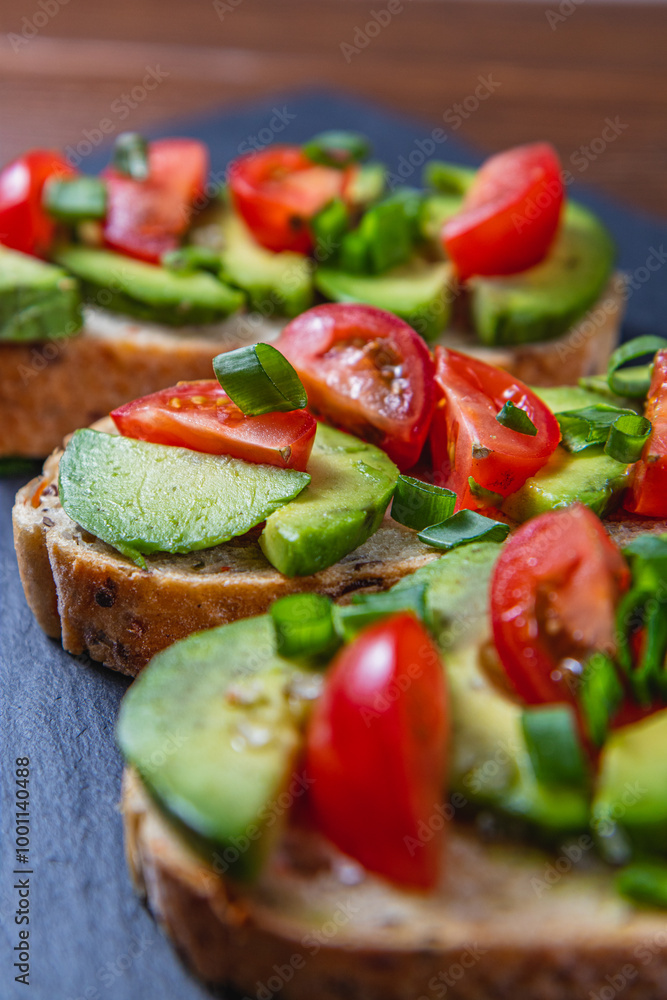 Avocado toast topped with tomato and green onion on a slice of carrot bread Avocado toast topped with tomato and green onion on a slice of carrot bread
