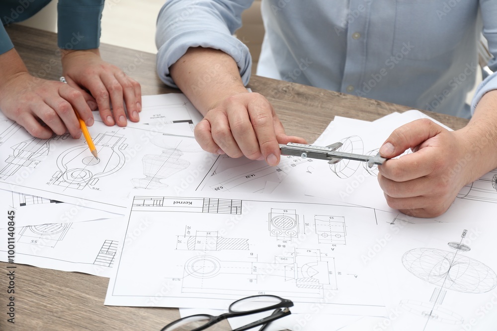 Engineers working with project, closeup. Different technical drawings on wooden table Engineers working with project, closeup. Different technical drawings on wooden table