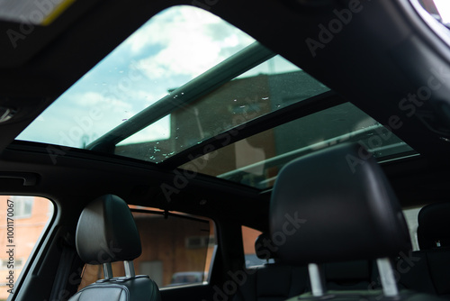 Polarised sunroof of luxurious automobile with urban sky scenery shot from inside of vehicle. Glass surface being more energy influenced by natural light at day
