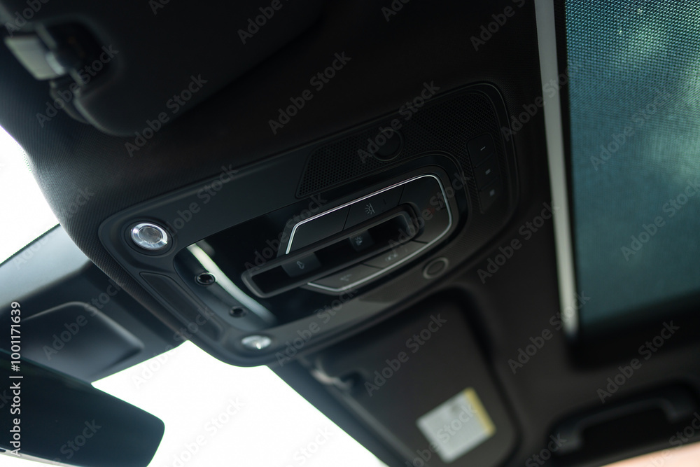 Fototapeta premium Close up view of interior cabin lights with dome-shaped cover attached to ceiling of modern car. Overhead controls of turning on or off illumination in cabin of vehicle