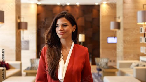 Confident young woman smiles as she stands in the sleek lobby of her company