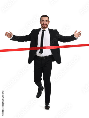 Young businessman in suit crossing red finish line on white background