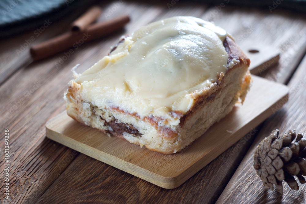 A bun with chocolate and cinnamon lies on a board on the table A bun with chocolate and cinnamon lies on a board on the table