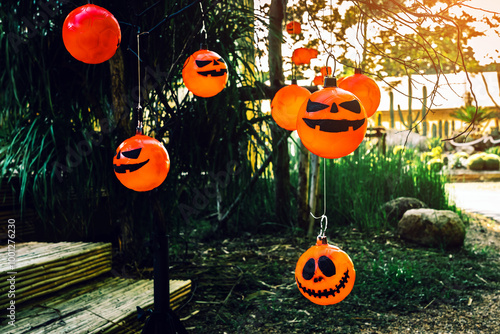 Many DIY head of Halloween Jack o Lantern Pumpkin with spooky smiling face hanging with ropes decorated on tree. Orange color of pumpkin heads. Happy Halloween concept. Traditional Halloween pumpkin. photo