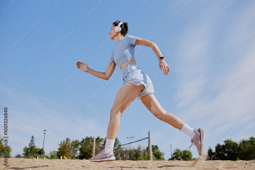Low angle shot of senior woman jogging and listening to music via headphones Low angle shot of senior woman jogging and listening to music via headphones