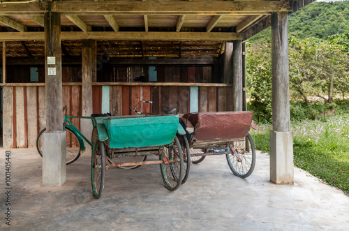 Old cycle rickshaws parked under a house in Kampot in Cambodia