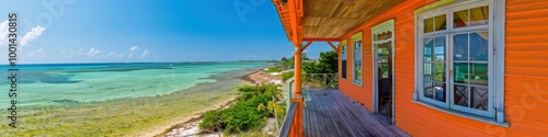 Cheerful orange coastal home with a wrap-around porch, overlooking the crystal-clear waters and soft sandy shore.