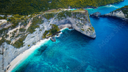 A stunning aerial view of Diamond Beach, located on the eastern side of Nusa Penida, Bali. This pristine beach is known for its white sandy shores, crystal-clear turquoise waters, and dramatic limesto photo