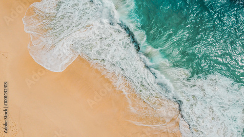 An aerial view of gentle ocean waves meeting the golden sands at Kelingking Beach, Nusa Penida, Indonesia. The vivid turquoise water creates a stunning contrast with the untouched beach below.
 photo