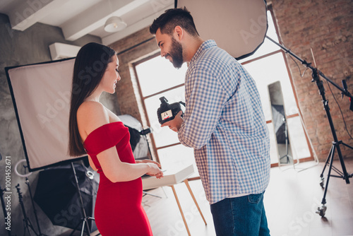 Photo of positive cameraman showing video of passionate seductive woman dressed red outfit indoors workplace studio photo